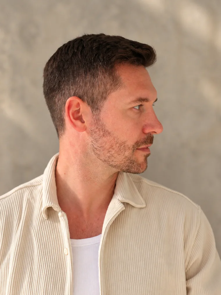 Till Schaumann im Profil vor einer Sichtbetonwand